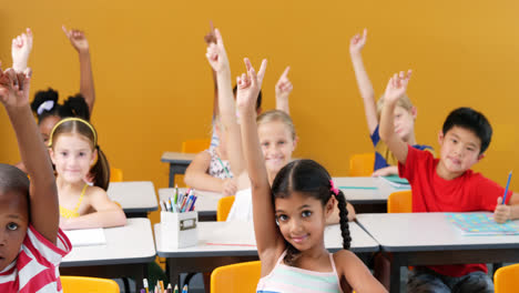 School-kids-raising-hands-in-classroom