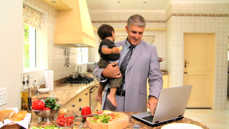 Man-holding-baby-and-failing-to-interest-him-in-laptop