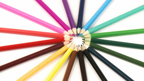 Zoom-in-on-colour-pencils-in-a-circle-turning-against-white