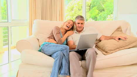 Couple-on-sofa-enjoying-a-programme-on-their-laptop