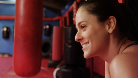 Smiling-female-boxer-standing-in-fitness-studio