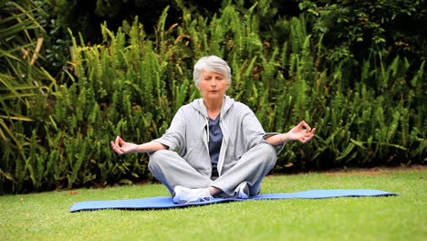 Mature-woman-doing-yoga-outdoors-on-a-mat-