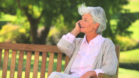 Mature-woman-phoning-on-a-public-bench