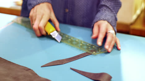 Mid-section-of-craftswoman-cutting-leather