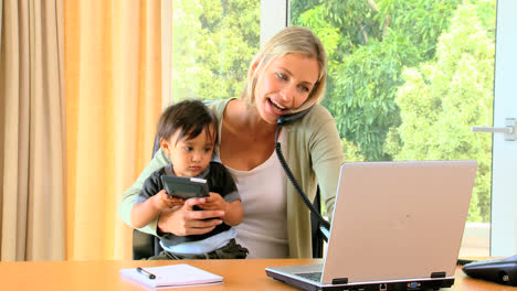 Woman-carrying-baby-and-working-on-laptop-