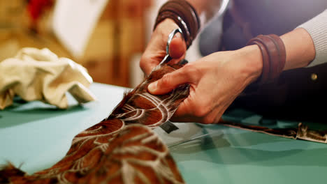 Mid-section-of-craftswoman-cutting-leather-with-scissors