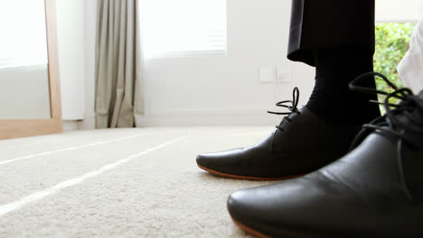 Man-tying-a-shoelaces-in-bedroom