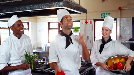 Head-chef-juggling-vegetables-and-colleagues-watching