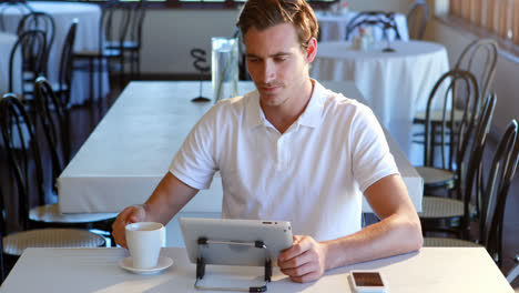 Man-having-cup-of-coffee-and-using-digital-tablet