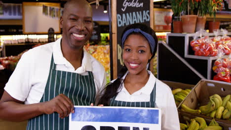 Smiling-staffs-holding-open-signboard-in-organic-section