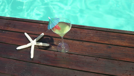 Cocktail-glass-and-fake-starfish-near-swimming-pool