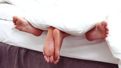 Paar-Füße-Ragen-Unter-Der-Bettdecke-Hervor