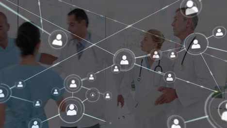Animation-of-network-of-connections-with-icons-over-diverse-doctors-discussing-work-in-hospital