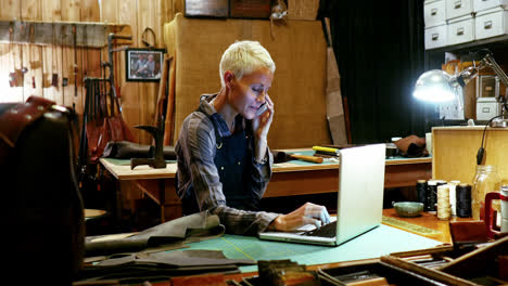 Craftswoman-using-laptop-while-talking-on-mobile-phone
