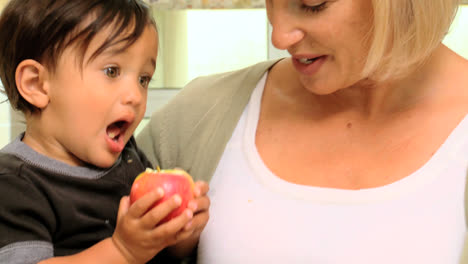 Baby-In-Den-Armen-Der-Mutter-Probiert-Einen-Roten-Apfel-