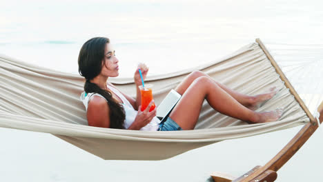Woman-relaxing-on-hammock-and-using-digital-tablet