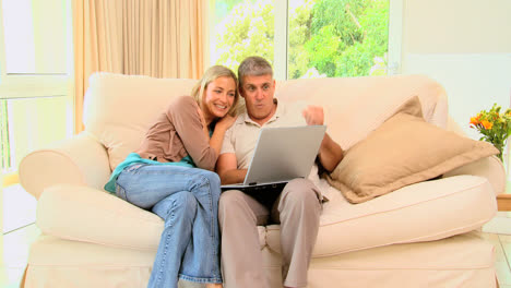 Young-couple-on-sofa-laughing-over-their-laptop