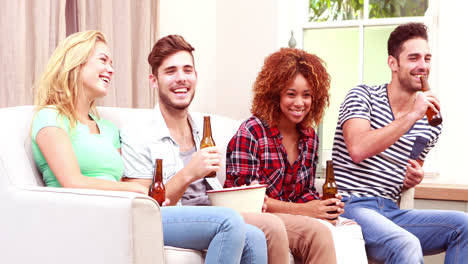 Lächelnde-Freunde-Vor-Dem-Fernseher,-Während-Sie-Popcorn-Essen-Und-Bier-Trinken