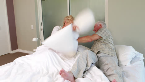 Senior-couple-having-a-pillow-fight