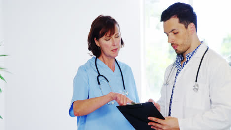 Krankenschwester-Und-Arzt-Diskutieren-über-Die-Zwischenablage-Im-Flur