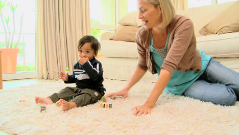 Junge-Mutter-Spielt-Mit-Ihrem-Baby-Auf-Teppich