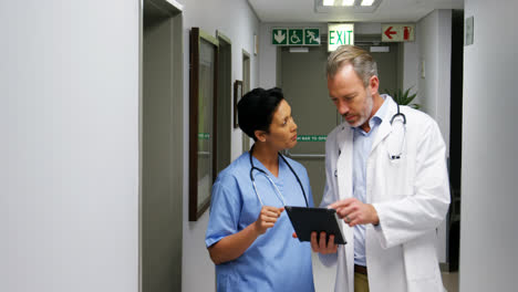 Male-doctor-and-colleague-discussing-over-digital-tablet