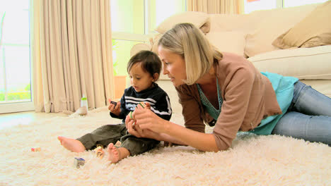 Young-mother-playing-with-baby-on-carpet