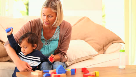 Young-woman-showing-her-baby-how-to-play-with-building-blocks