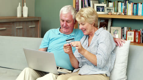 Senior-couple-using-laptop-and-holding-credit-card