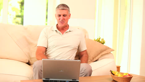 Mann-Mittleren-Alters-überglücklich-über-Das,-Was-Er-Auf-Seinem-Laptop-Sieht