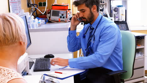 Doctor-sitting-at-his-desk-and-talking-on-phone