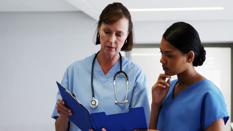 Nurse-and-doctor-discussing-over-clipboard