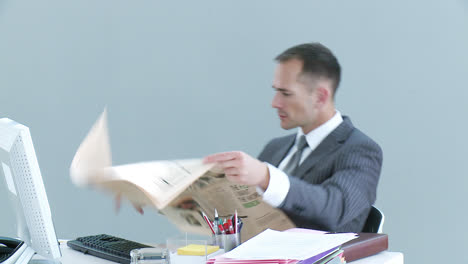 Businessman-in-office-reading-a-newspaper-and-talking-on-phone