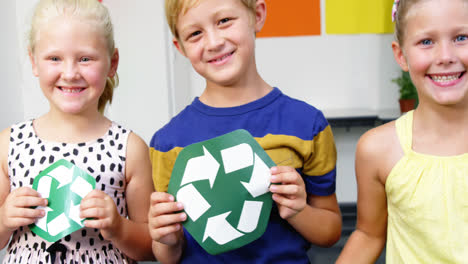 Schulkinder-Halten-Recycling-Symbole-Und-Globus-Im-Klassenzimmer