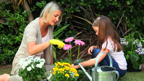 Mother-and-daughter-smelling-pink-flowers-in-garden