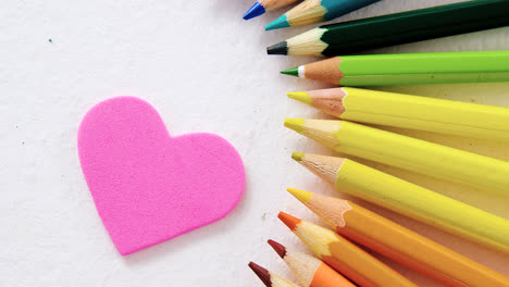 Colored-pencils-arranged-in-semi-circle-with-heart-on-white-background