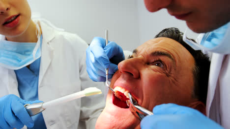 Dentists-examining-a-male-patient-with-tools