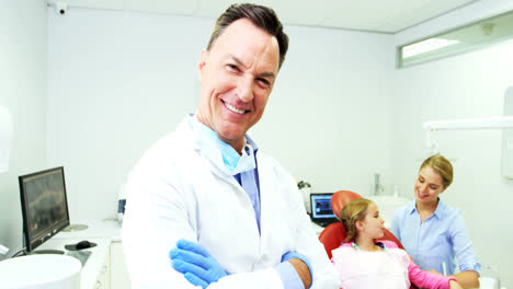 Lächelnder-Zahnarzt,-Der-Mit-Verschränkten-Armen-In-Der-Zahnklinik-Steht