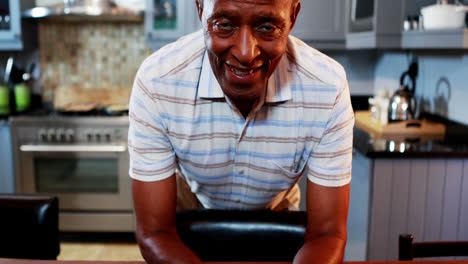 Portrait-of-senior-man-smiling-at-camera-in-kitchen