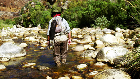 Fly-fisherman-walking-in-river-with-fishing-rod