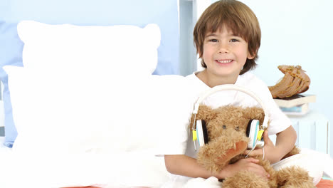 Little-boy-and-teddy-bear-listening-to-music-on-bed