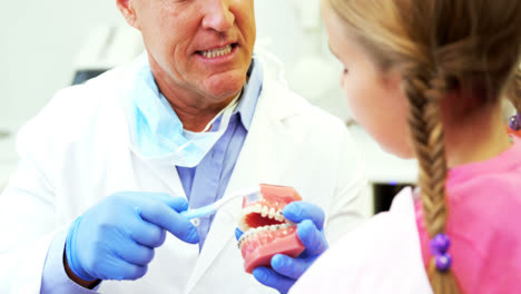 Dentista-Mostrando-A-Un-Paciente-Joven-Cómo-Cepillarse-Los-Dientes