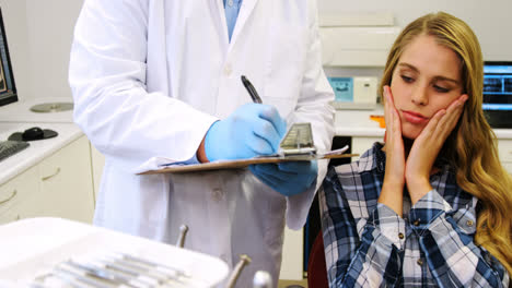 Dentist-preparing-dental-report-of-female-patient