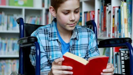 Disabled-schoolboy-on-wheelchair-reading-book-in-library