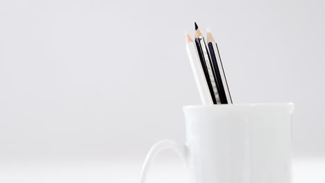 Black-and-white-colored-pencils-kept-in-mug-on-white-background