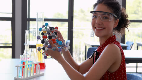 Porträt-Einer-Glücklichen-Schülerin,-Die-Im-Labor-Mit-Einem-Molekülmodell-Experimentiert