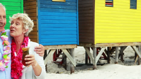 Senior-couple-having-drink-near-colorful-beach-hut