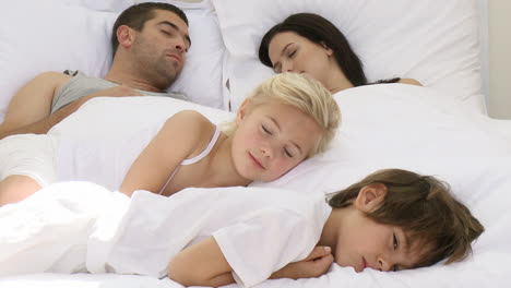 Smiling-daughter-relaxing-with-her-brother-and-parents-in-bed