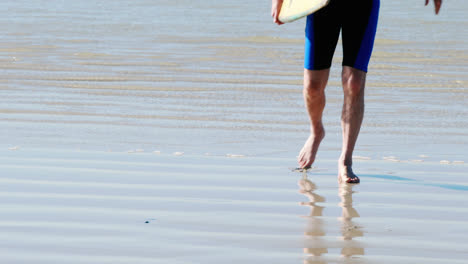 Senior-man-with-surfboard-walking-on-beach