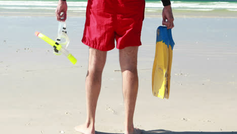 Senior-man-with-flippers-and-diving-mask-standing-on-beach